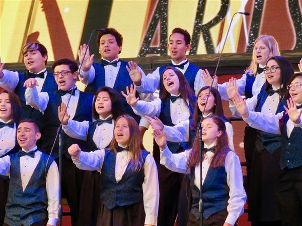 Close up of several high school chorale students singing on stage Close up of several high school chorale students singing on stage